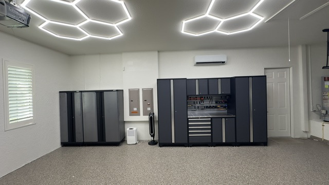 Wide garage view with finished floor, cabinets and geometric ceiling lights