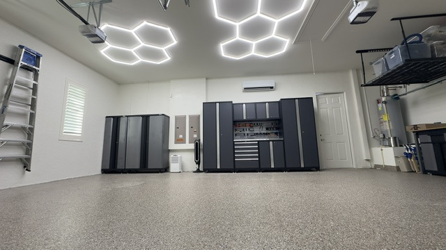 Finished garage with decorative floor, cabinets and bright ceiling lighting