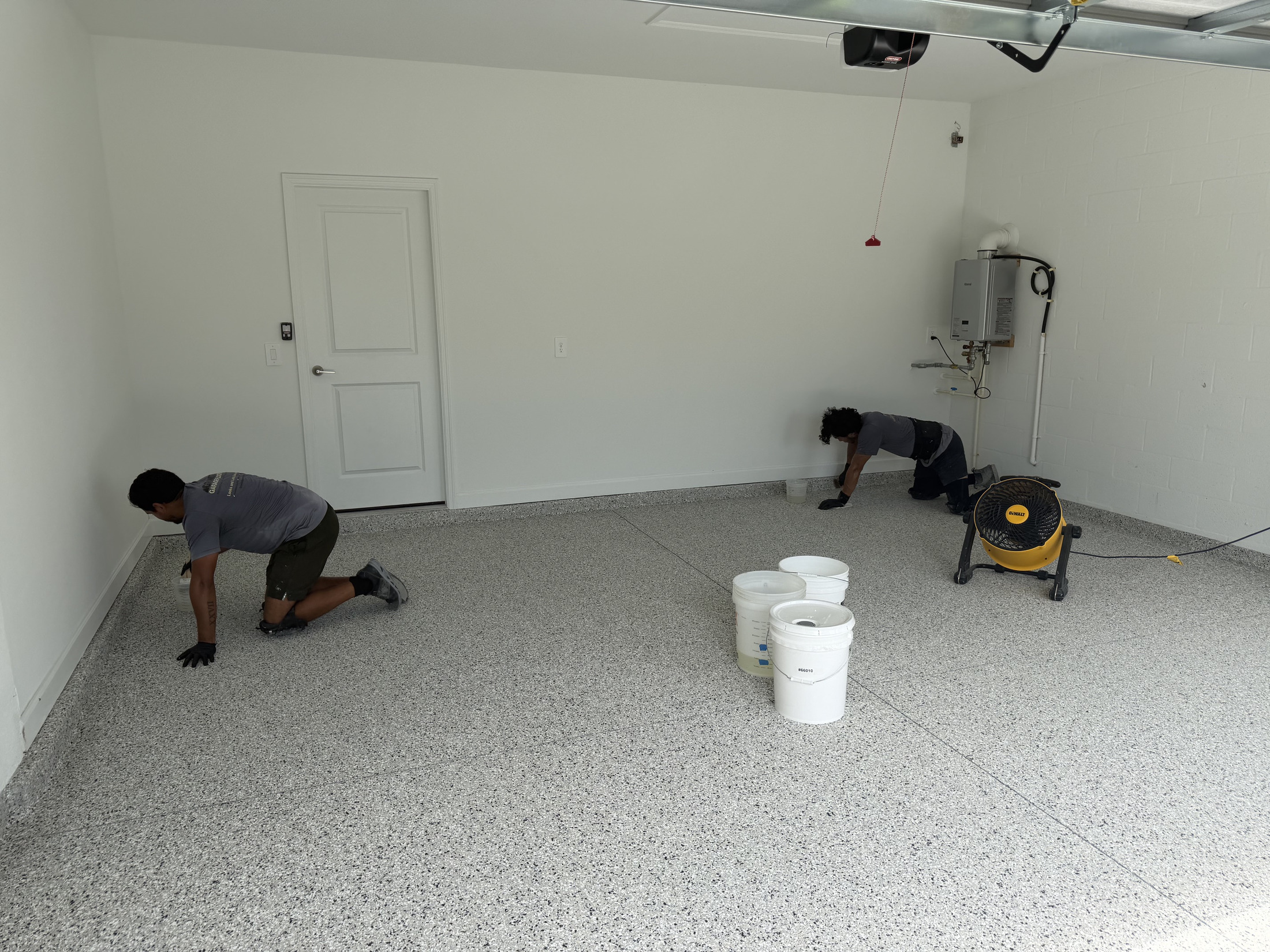 Professional concrete preparation and coating work underway in a garage
