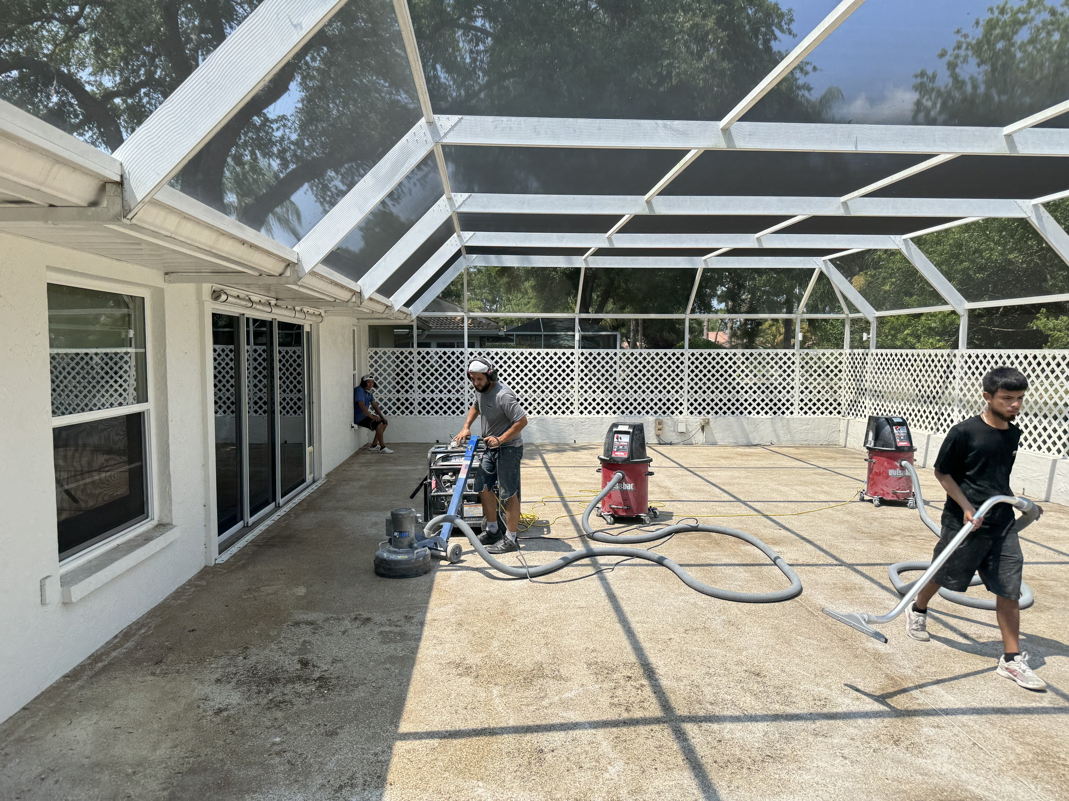 Covered patio concrete being mechanically prepared for a coating system
