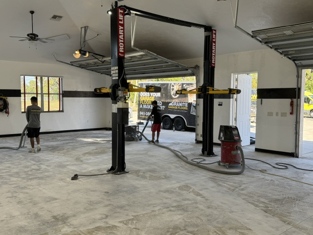 Base coating stage underway on a garage floor around vehicle lifts