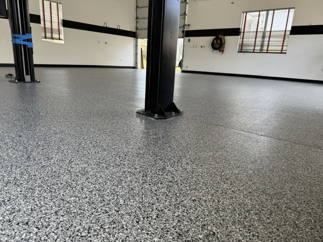 Wide completed garage floor with vehicle lift and workshop equipment