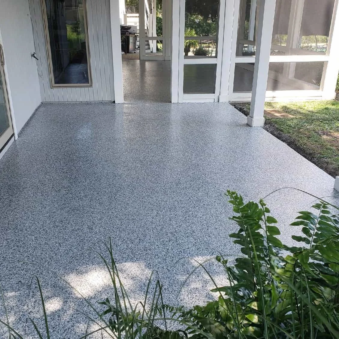 Gray coated patio floor beside screened doors and a garden