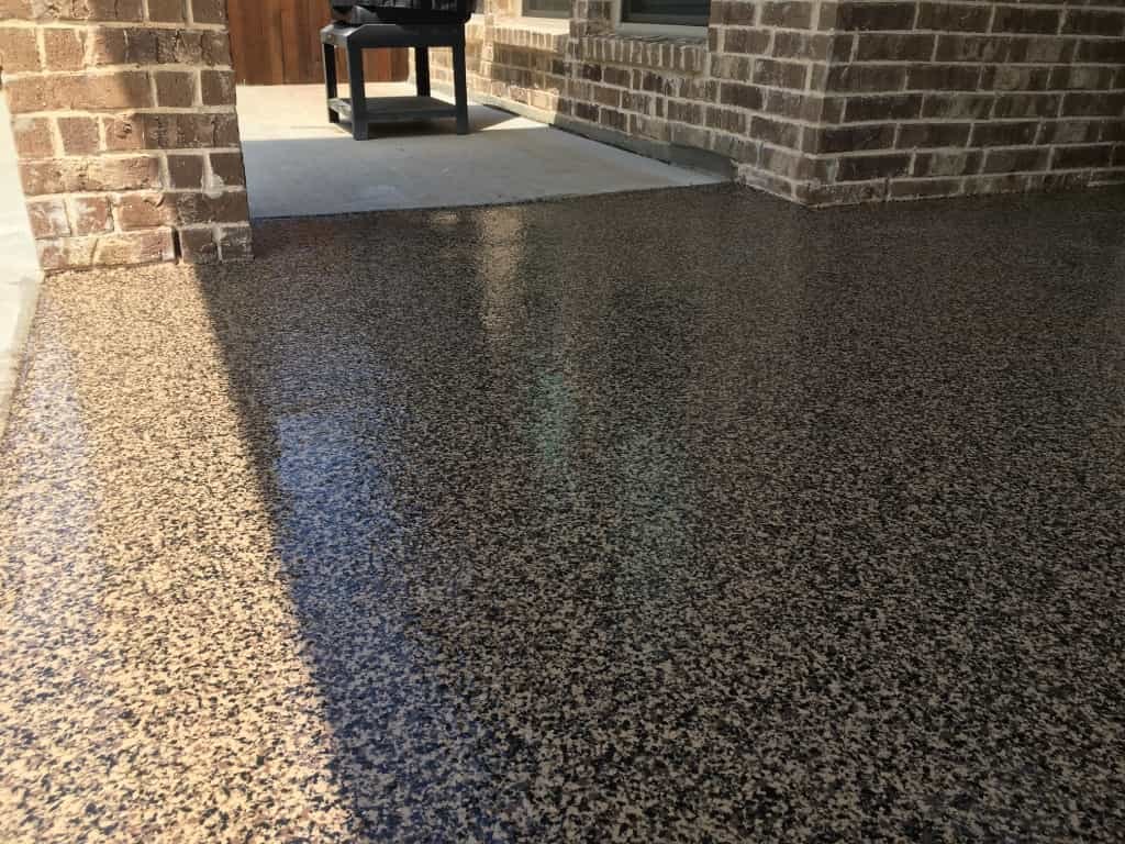 Decorative concrete coating on a covered patio beside a brick wall